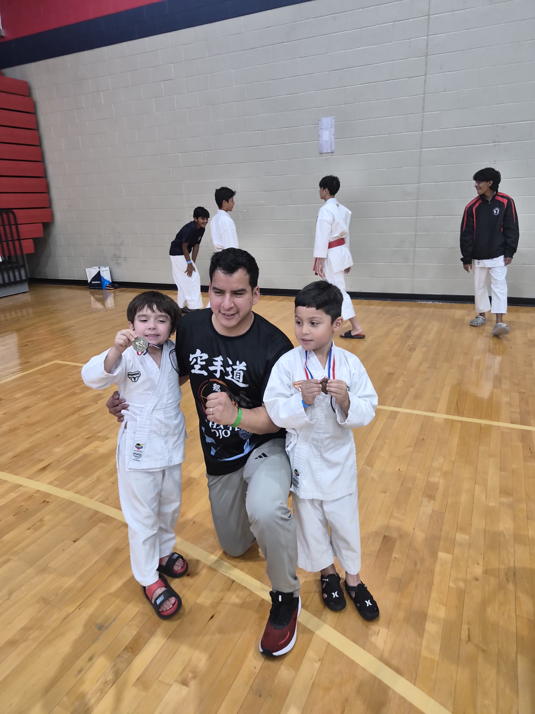 A family supporter posing with two young karate students